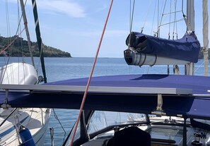 Un voilier doté d’un pont couvert, d’un treuil et offrant une vue sur la mer et une étendue de terre lointaine.