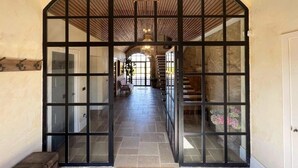 A hallway with a large arched doorway, stone flooring, and a staircase leading to an upper level. - Castillo de Corvinos (Albero Alto)