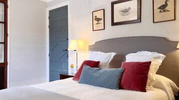 A neatly made bed with pillows, a lamp, and framed pictures on the wall.