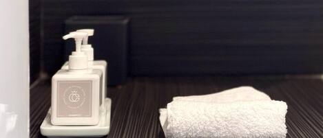 A bathroom with a white towel and a white bottle of shampoo on a textured floor.