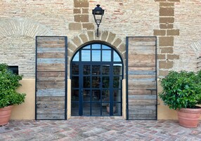 Una entrada de edificio con puerta de madera, pared de piedra y planta en maceta.