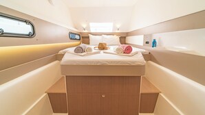 Een compacte, goed verlichte hut met een bed, opbergvakken en een klein raam.