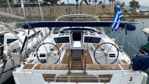 A boat named 'ALISA' docked at a marina with a wooden deck and a blue flag.