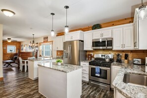 A modern kitchen with white cabinets, stainless steel appliances, and a granite countertop. - Twilight Tides-Lake Front/HotTub/6 Min GOTL Strip (Ashtabula)
