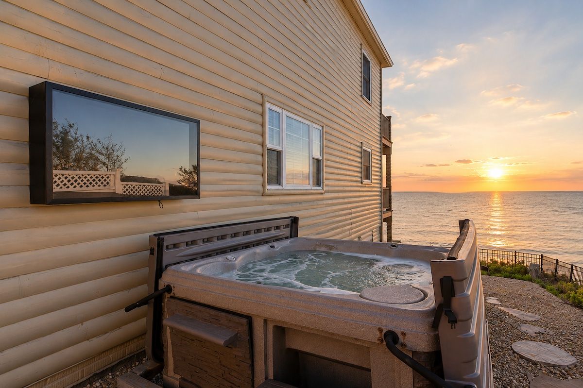 A hot tub outside a house with a view of the sunset over the water.