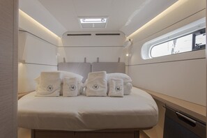 A compact, well-lit room with a bed, a skylight, and a window.