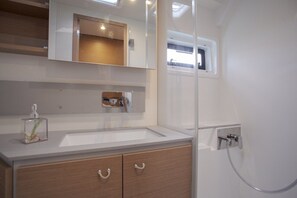 Un baño moderno con un espejo grande, un lavabo, armarios de madera y una ducha.