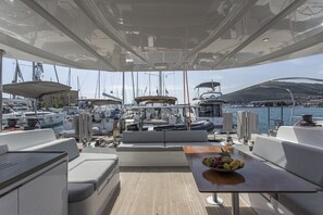 Ein Yachthdeck mit Sitzgelegenheiten, einem Tisch mit Obst und Blick auf eine Marina.