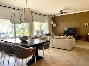 Ein modernes Wohnzimmer mit Essbereich, Fernseher und Deckenventilator.