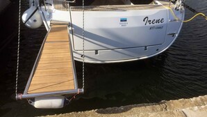 A boat named 'Irene' docked at a marina with a wooden deck, a steering wheel, and a motor on the starboard side. - Sun-Kissed Sailing Adventure in Islas Esporadas (Skiathos)
