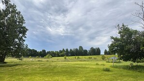 Eine Wiese mit einer hölzernen Bank und einem Betongebäude.