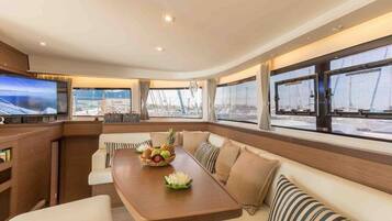 Un intérieur moderne comprenant un coin repas, des sièges confortables, un téléviseur et de grandes fenêtres offrant une vue sur la mer.