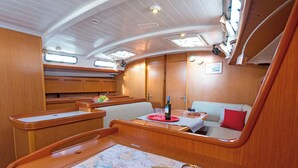 Une cuisine compacte avec des meubles en bois, une table à manger avec un plateau rouge et un coin salon agrémenté d’un coussin rouge.