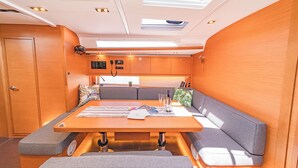 Een compact interieur met een eettafel, zachte zitting, een bedieningspaneel en een dakraam.