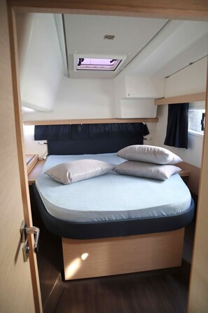 A bunk bed with a skylight, a bedside table, and a window with curtains. - Sun-Kissed Sailing Adventure in Islas Sarónicas (Alimos)