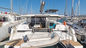 Un port de plaisance où sont amarrés de nombreux bateaux, avec un bateau central doté d’un espace de repos couvert et d’une petite table.