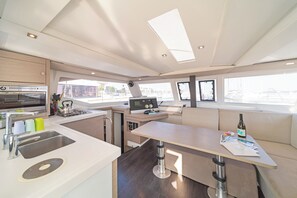 A modern kitchen with a built-in stove, a microwave, and a sink. There is a dining area with a table and chairs, and a window providing a view of the outside.