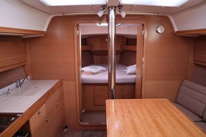A compact interior with a bunk bed, a sink, and a table. - Sun-Kissed Sailing Adventure in Islas Sarónicas (Alimos)