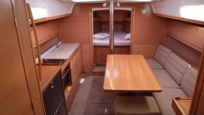 Een compact RV-interieur met een kitchenette, een eethoek en een slaapplaats.