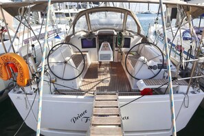 A boat's deck with a steering wheel, Garmin navigation system, and a lifebuoy. - Sun-Kissed Sailing Adventure in Islas Sarónicas (Alimos)