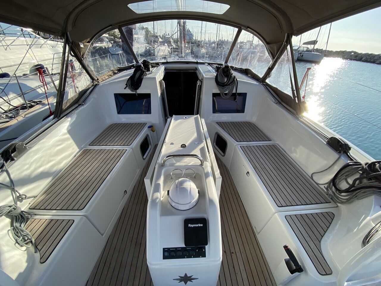 Le pont d’un bateau, avec un espace salon central, un volant et un système de navigation Raymarine.