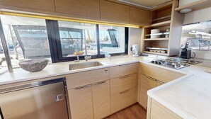 Une cuisine moderne dotée d’une grande fenêtre, d’appareils électroménagers en acier inoxydable et de meubles de rangement en bois.