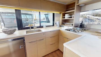 A modern kitchen with a large window, stainless steel appliances, and wooden cabinetry.
