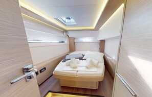 A modern, compact bedroom with a skylight, a bed with towels, and a wooden finish. - Sun-Kissed Sailing Adventure in Islas Sarónicas (Alimos)