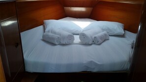 A single bed with white linens and two rolled towels. - Sun-Kissed Sailing Adventure in Islas Sarónicas (Alimos)