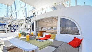 Das Interieur einer Yacht mit Essbereich, gepolsterten Sitzgelegenheiten und Blick auf den Yachthafen.