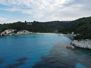 Eine Küstenlandschaft mit klarem, blauem Wasser, felsigen Ufern und einer hügeligen Kulisse.