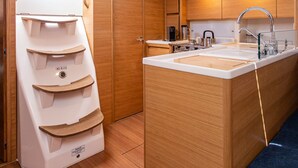 Eine kleine Küche mit integriertem Spülbecken, Holzschränken und einem kleinen Fenster.