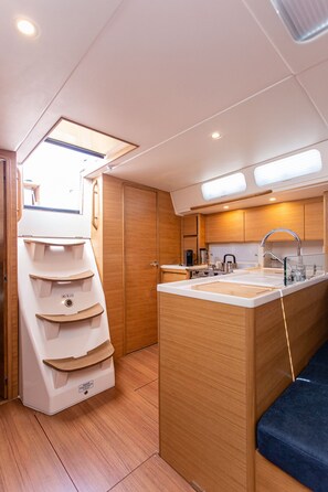 Eine kleine Küche mit integriertem Spülbecken, Holzschränken und einem kleinen Fenster.