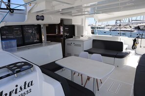 A boat interior with a dining area, a small kitchenette, and a seating area. - Sun-Kissed Sailing Adventure in Islas Sarónicas (Alimos)