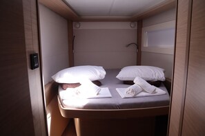 A compact, well-lit room with a single bed, pillows, and neatly folded towels. - Sun-Kissed Sailing Adventure in Islas Sarónicas (Alimos)