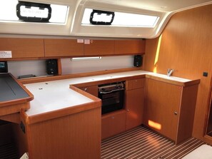 A compact galley with a stove, cabinets, and a small sink. - Sun-Kissed Sailing Adventure in Islas Sarónicas (Alimos)