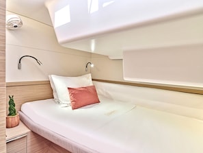 A modern hotel room with a bed, a wall-mounted security camera, a bedside table with a plant, and a nightstand.