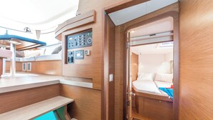 A compact, well-lit interior with a control panel, a bed with pillows, and a small seating area. - Sun-Kissed Sailing Adventure in the Stunning Islas Cícladas (Paros)