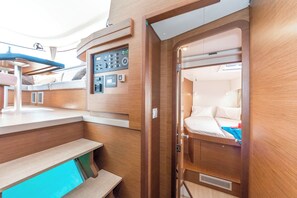 A compact, well-lit interior with a control panel, a bed with pillows, and a small seating area.
