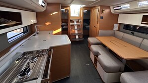 Een compact camperinterieur met een kitchenette, een eethoek en een slaapvertrek.