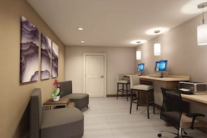 Ein Hotelzimmer mit Schreibtisch, zwei Stühlen, einer Couch, einem Fernseher und Bildern an der Wand.