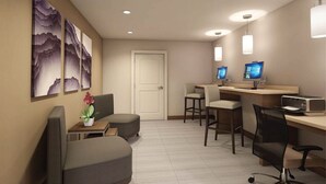 Une chambre d’hôtel équipée d’un bureau, de deux chaises, d’un canapé, d’une télévision et d’œuvres d’art accrochées au mur.