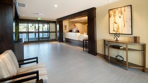 A reception area with a receptionist desk, a large abstract painting, and a seating area with chairs. - 2BR King Suite w/ Full Kitchen | Fire Pit + Pool (Scottsdale)