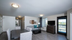 A modern living room with a dining area, a sofa, a TV, and a window with a view. - 2BR King Suite w/ Full Kitchen | Fire Pit + Pool (Scottsdale)