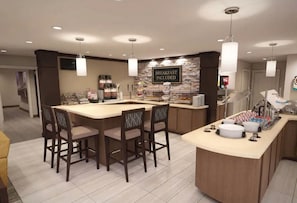 Un comptoir où l’on prend le petit-déjeuner, avec un panneau indiquant que le petit-déjeuner est inclus, un espace dédié au café et un buffet.