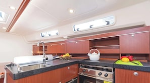 A compact galley with a sink, stove, and cabinets. - Sun-Kissed Sailing Adventure in the Saronic Islands (Laurium)
