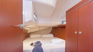 A compact cabin with a bed, a wardrobe, and a small overhead storage space.