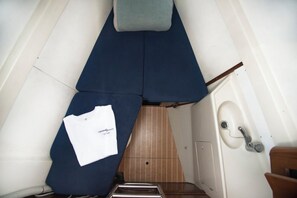 A narrow, angled room with a blue bed, a white towel, and a wooden panel wall. - Sun-Kissed Sailing Adventure in Islas Sarónicas (Alimos)