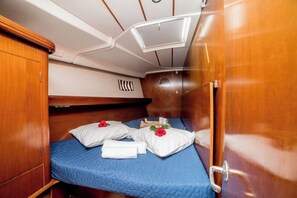 A compact cabin with a bunk bed, a small table with a book and a cup, and a window with a view of the sea. - Sun-Kissed Sailing Adventure in Islas Sarónicas (Alimos)