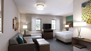 Een hotelkamer met een bank, twee bedden, een televisie en een schilderij aan de muur.